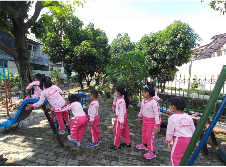 Belajar sabar dan berbagi giliran saat antre bermain perosotan dapat membantu mengembangkan kemampuan sosial-emosional siswa PAUD Asoka.